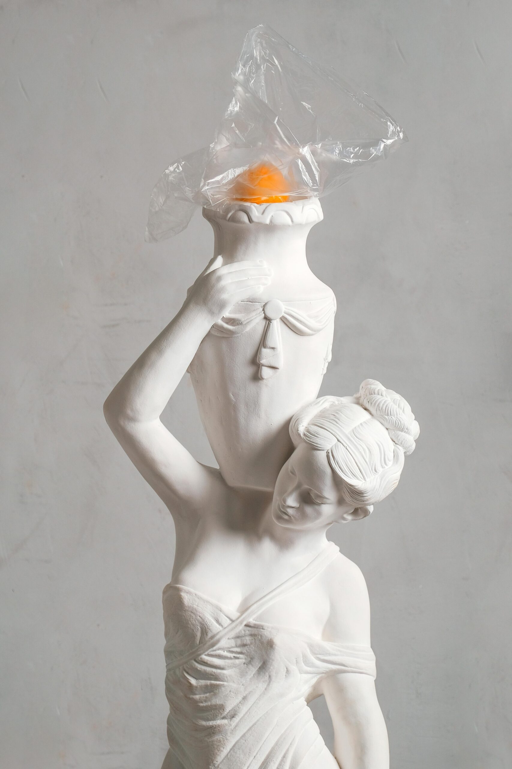 Intriguing sculpture of a woman with a vase on her head, wrapped in plastic.